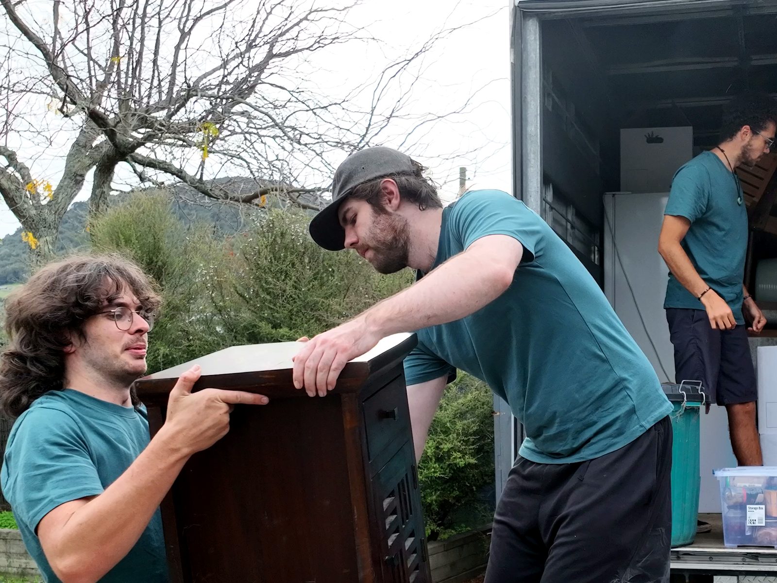 Two FLYTTE movers lifting a cabinet into the truck together